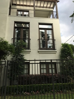 Stucco front with brown windows & wrought iron fence